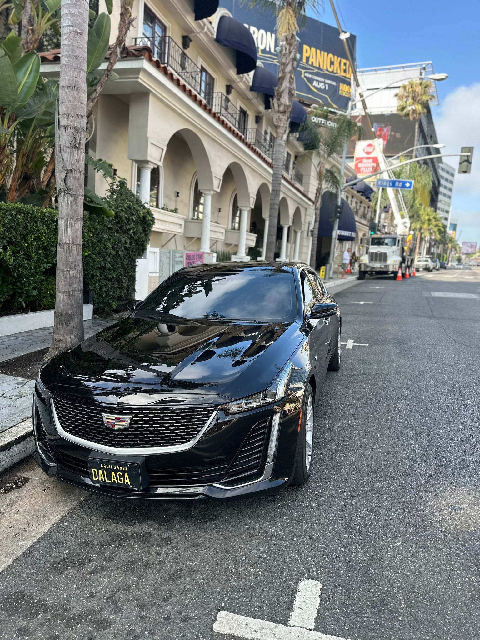 Black sports car parked on a steep street beside ornate buildings and a police sign.