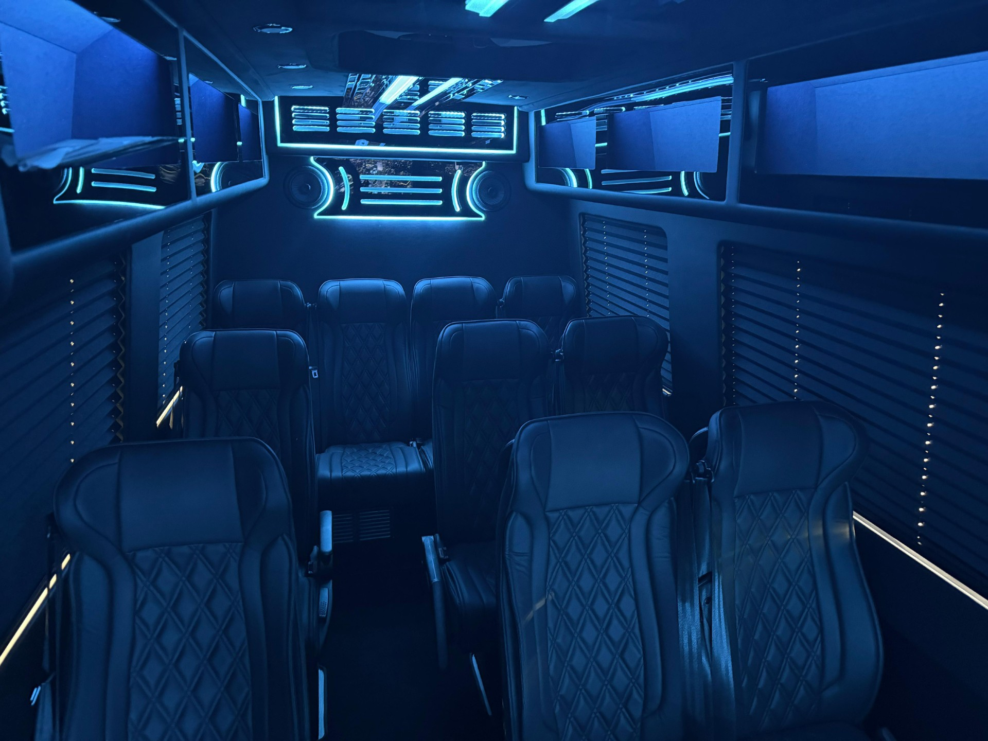 Blue-lit luxury van interior with leather captain’s seats and LED accent lighting