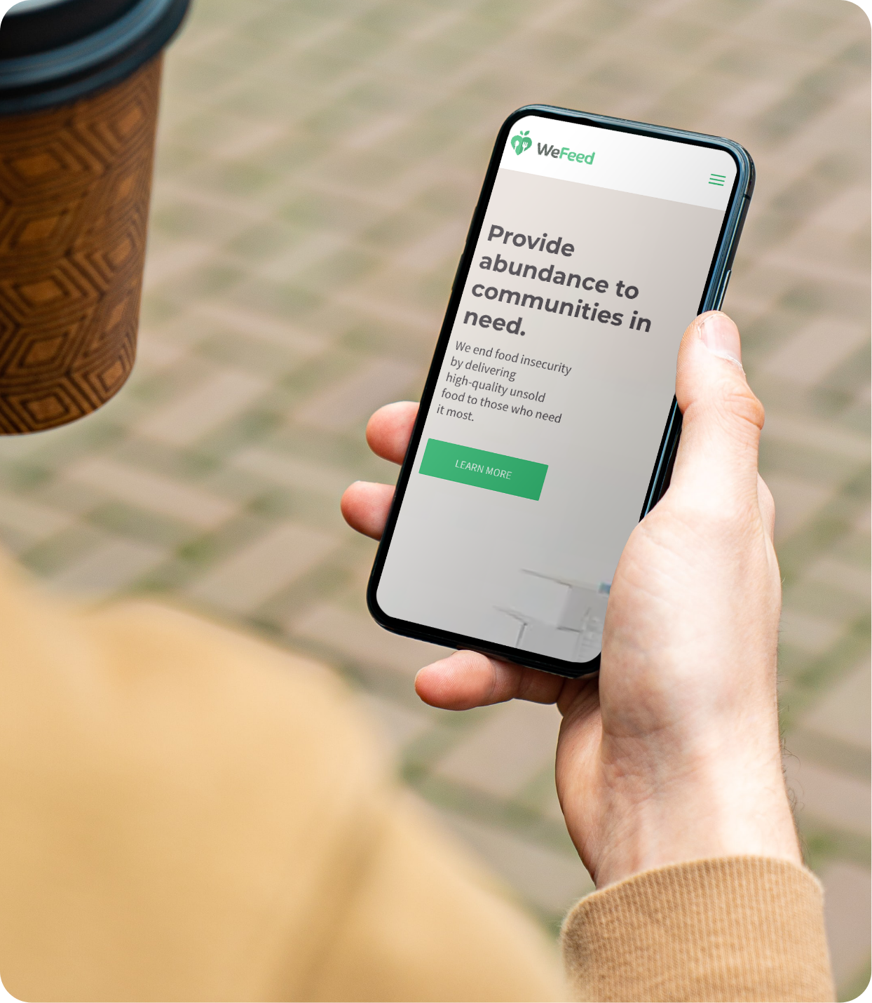 We Feed website template displayed on mobile as man holds cellphone