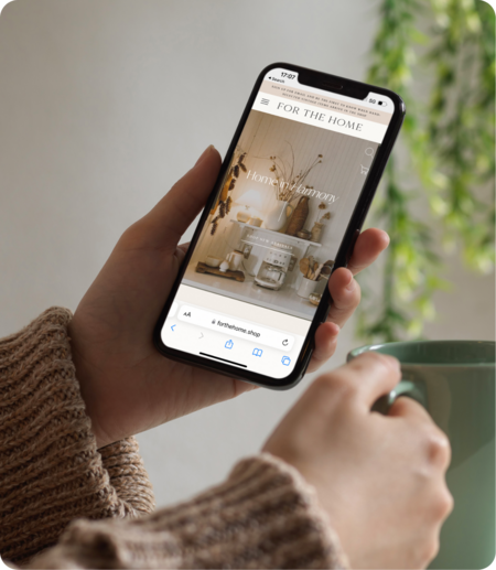 Home By Design’s website template displayed on mobile as man holds cellphone