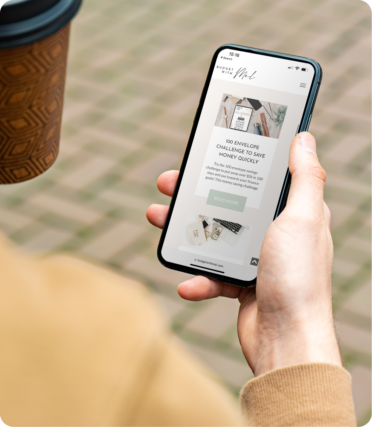 Budget with Mel website displayed on mobile as man hold cellphone