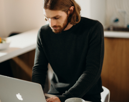 man with a beard looking at his MacBook