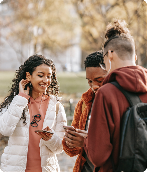 3 young people smiling and looking at their phones