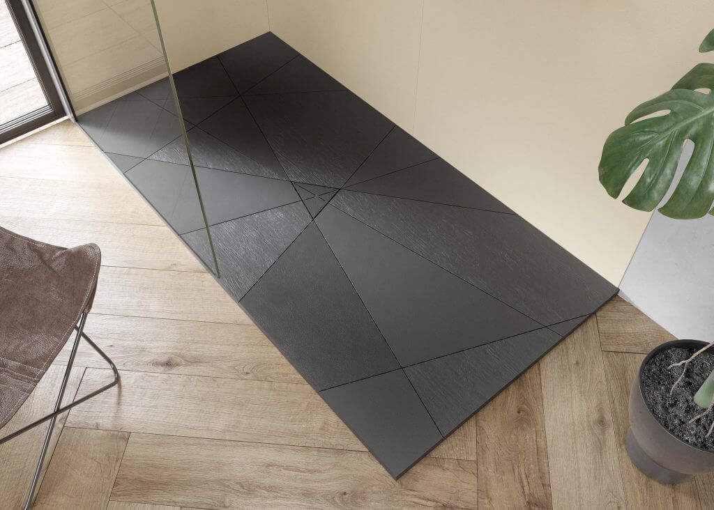 Un tappetino da doccia nero è appoggiato su un pavimento di legno accanto a una sedia e una pianta.