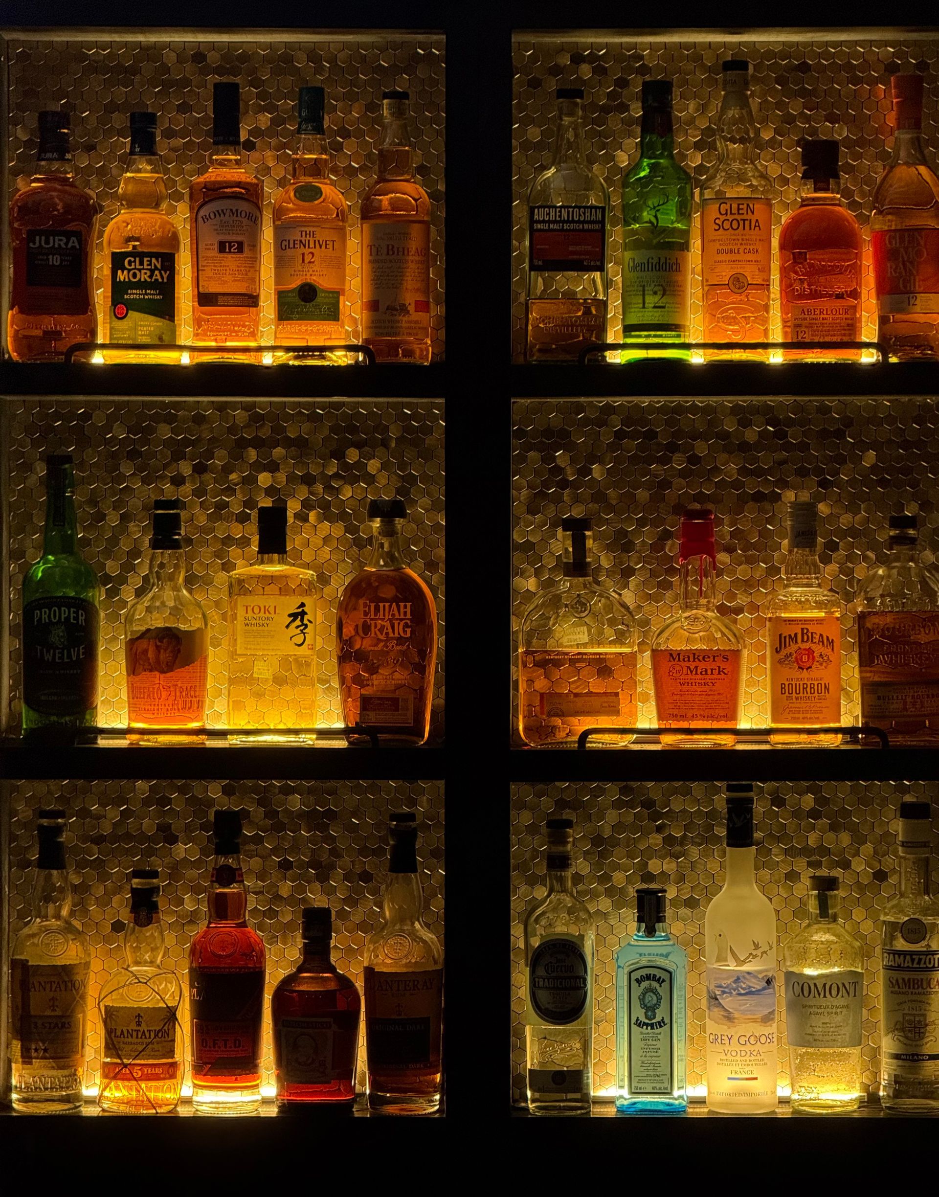 Illuminated bottles on backlit shelves in a dim bar or liquor display