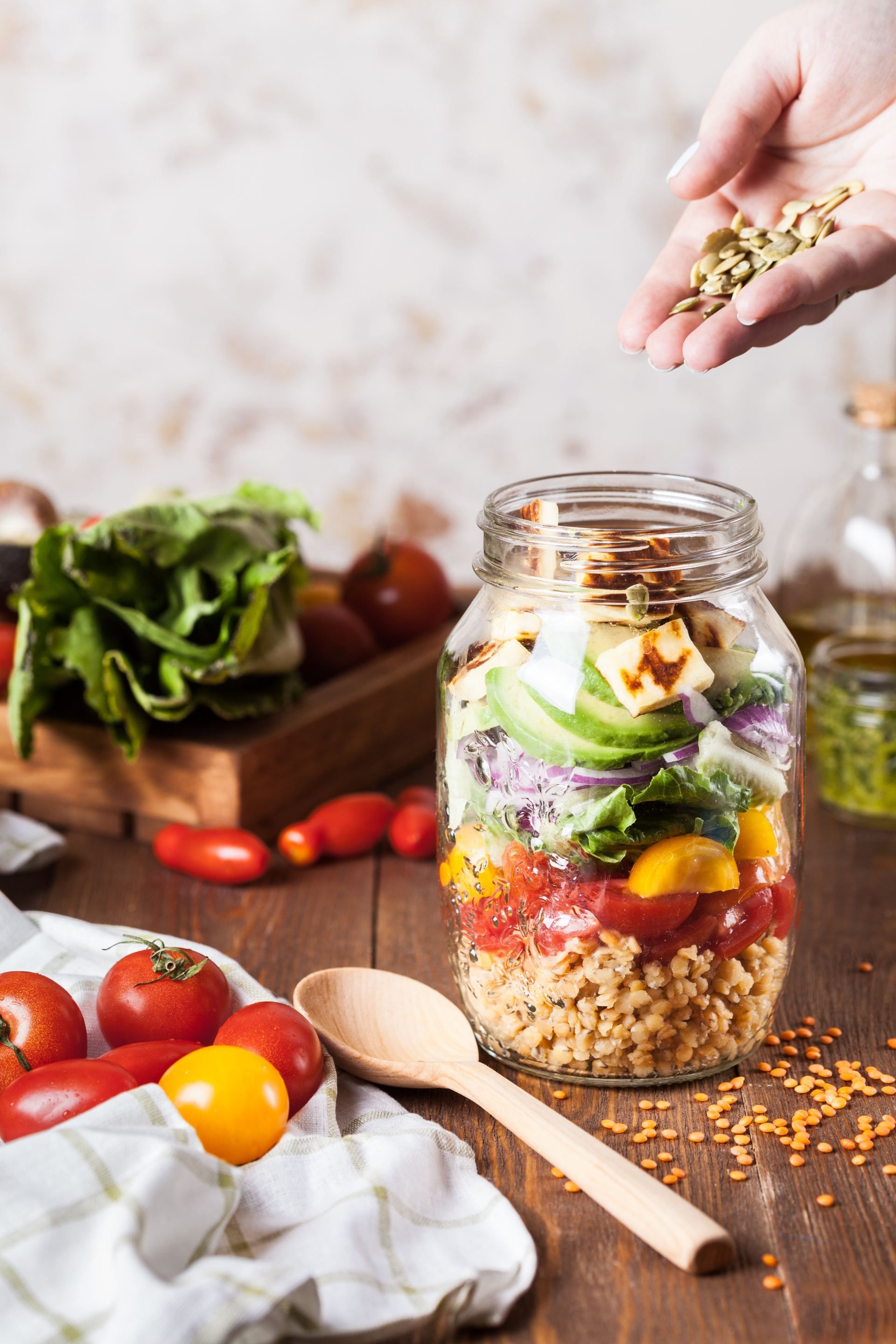 Salade in een pot: ingrediënten op een houten tafel opstapelen, bestrooid met linzen.