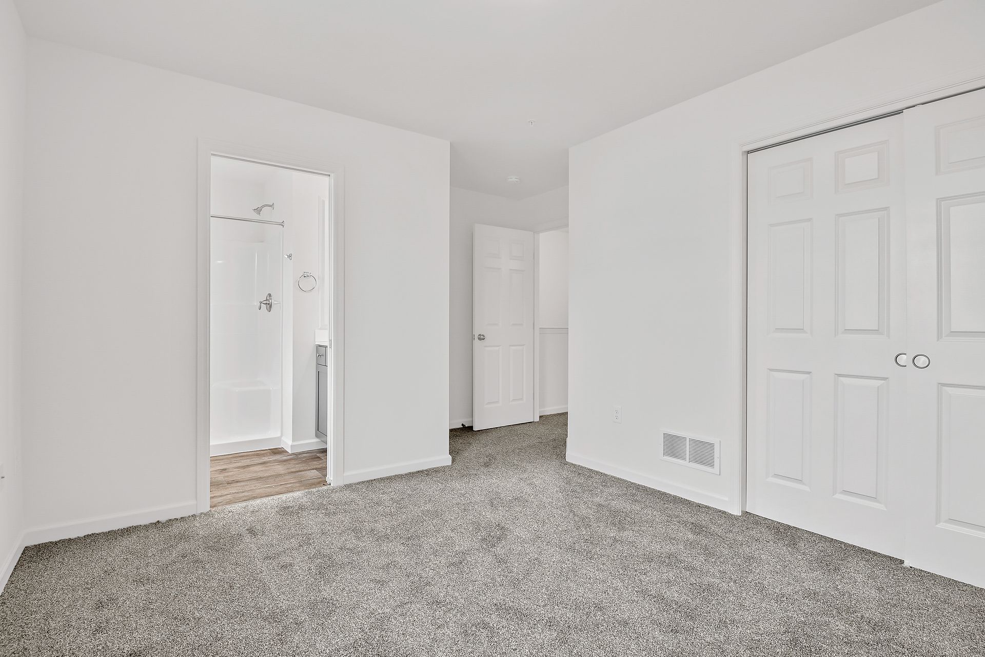 An empty bedroom with a carpeted floor and white walls.