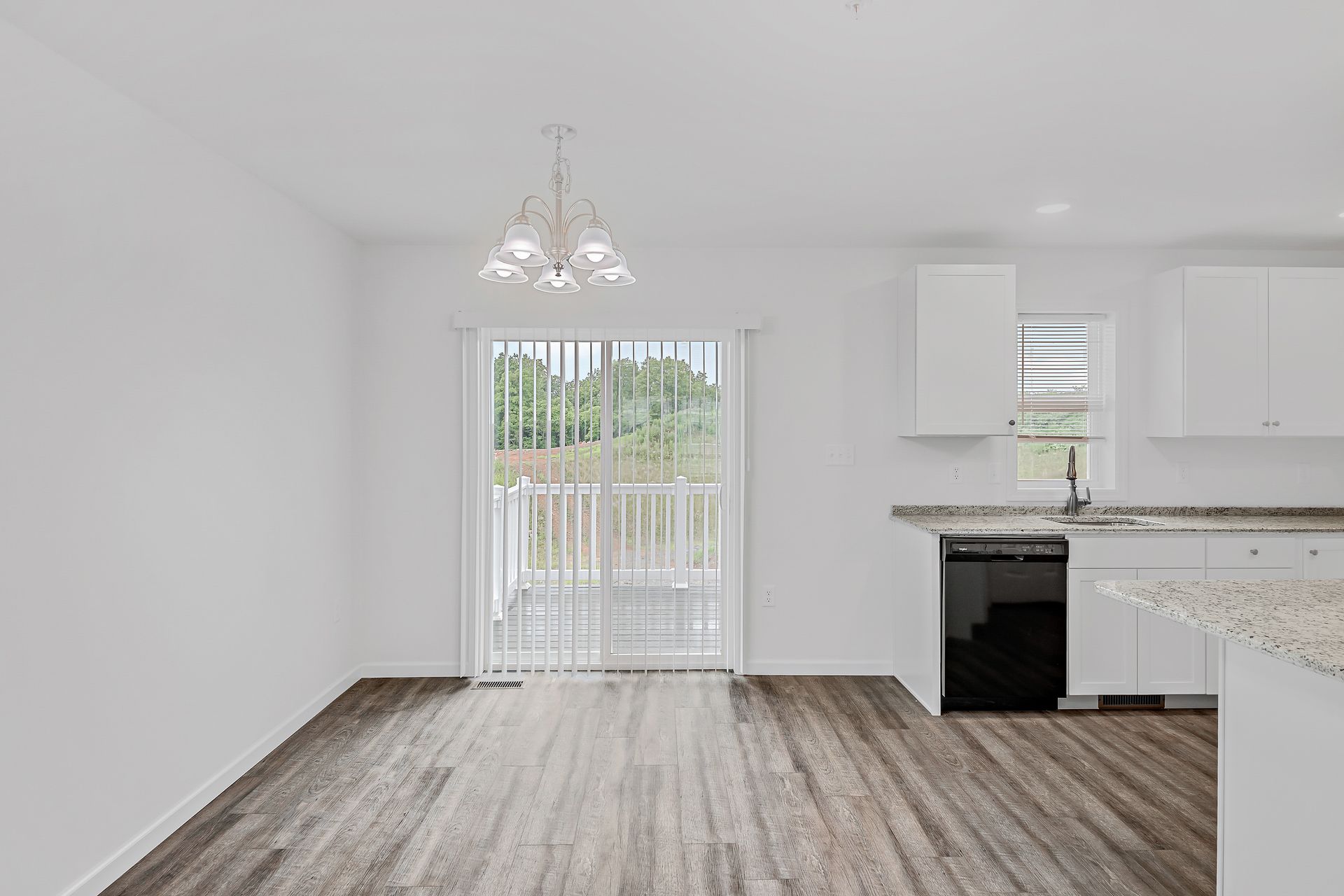 An empty room with hardwood floors and a sliding glass door leading to a balcony.