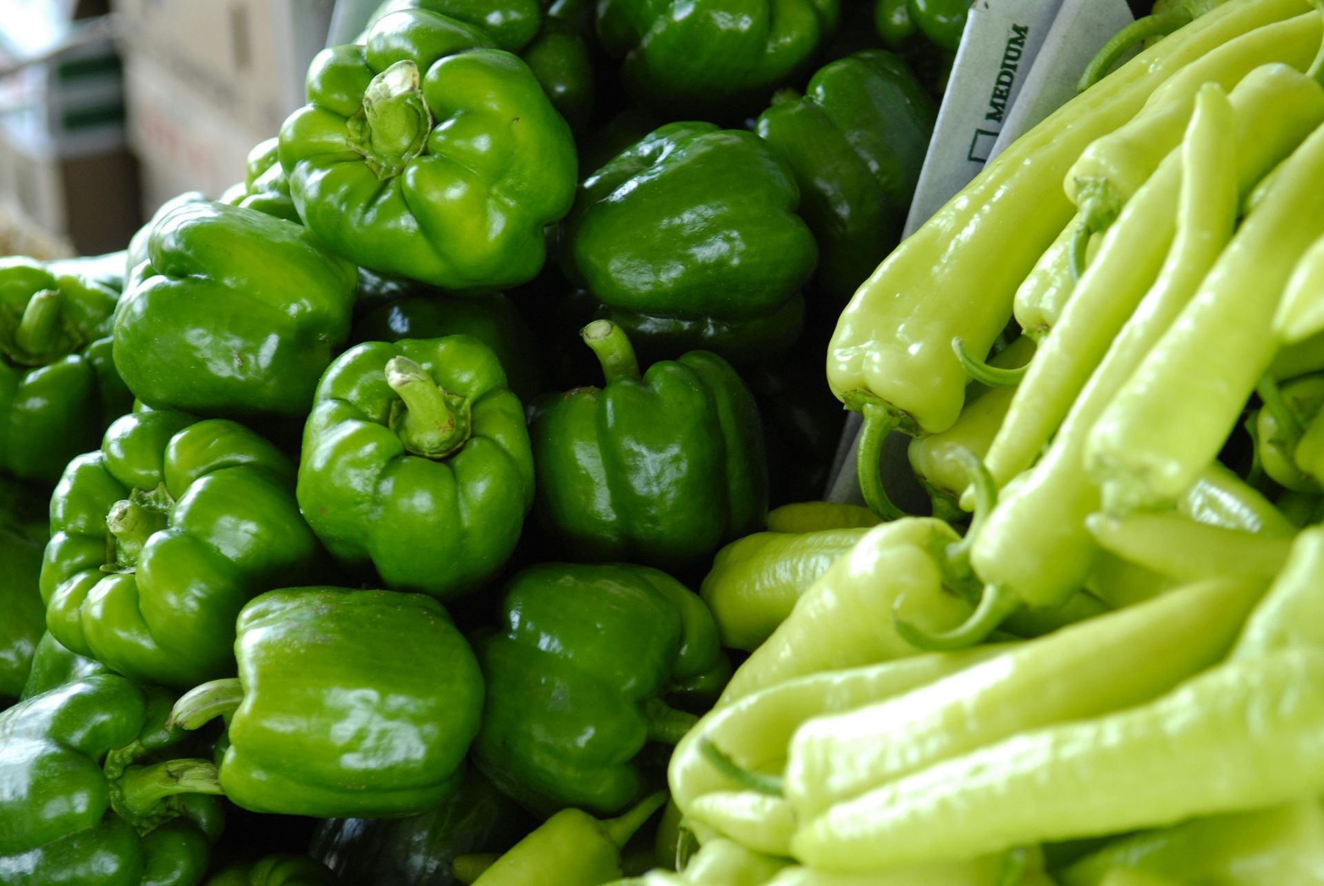 Green bell peppers and long, light green peppers piled together.