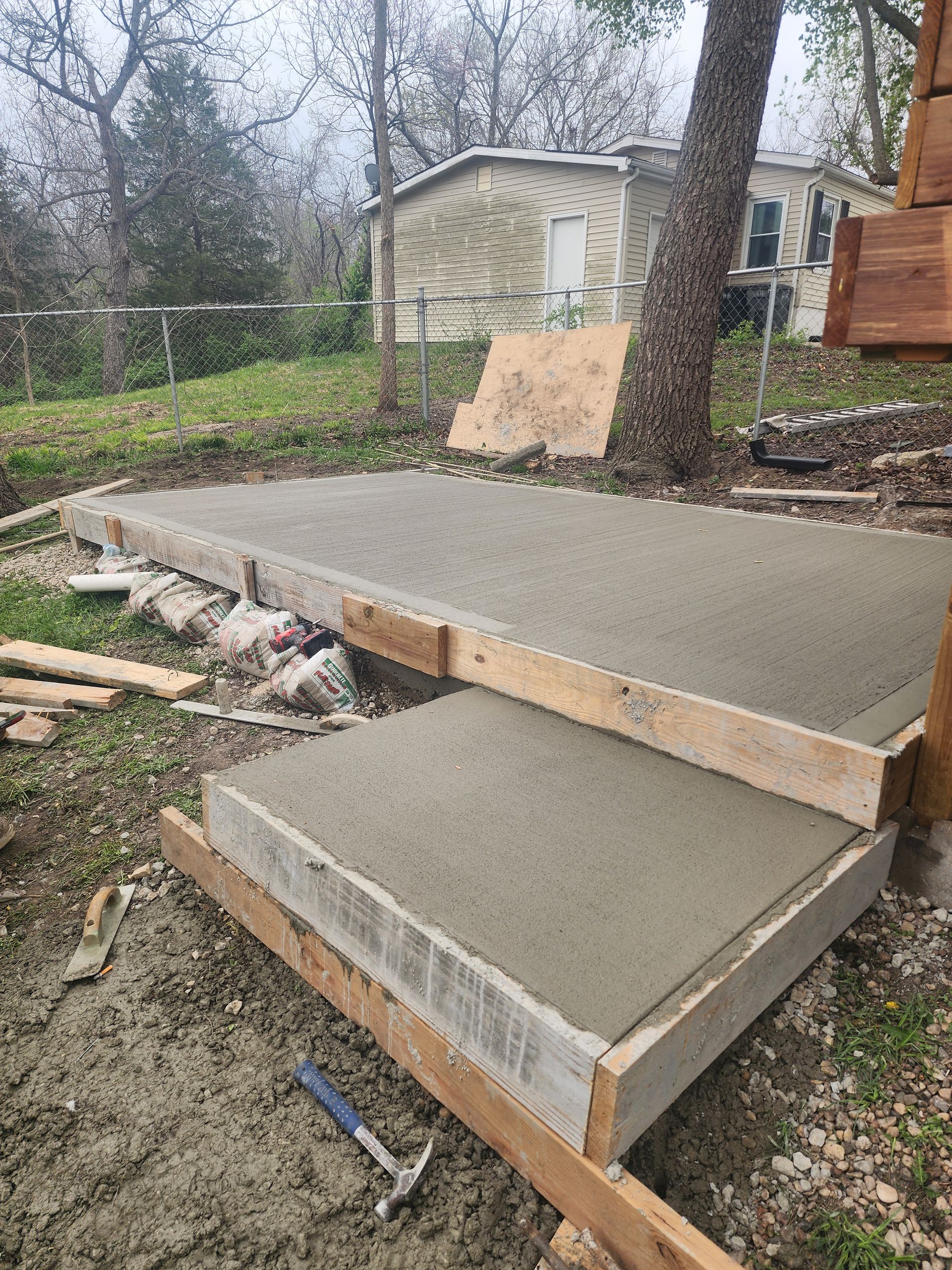 Freshly poured concrete steps under construction in a backyard, with wooden formwork still in place.