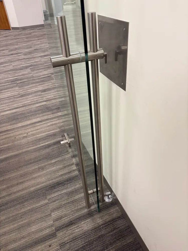 Glass door handle and latch on a carpeted hallway wall.