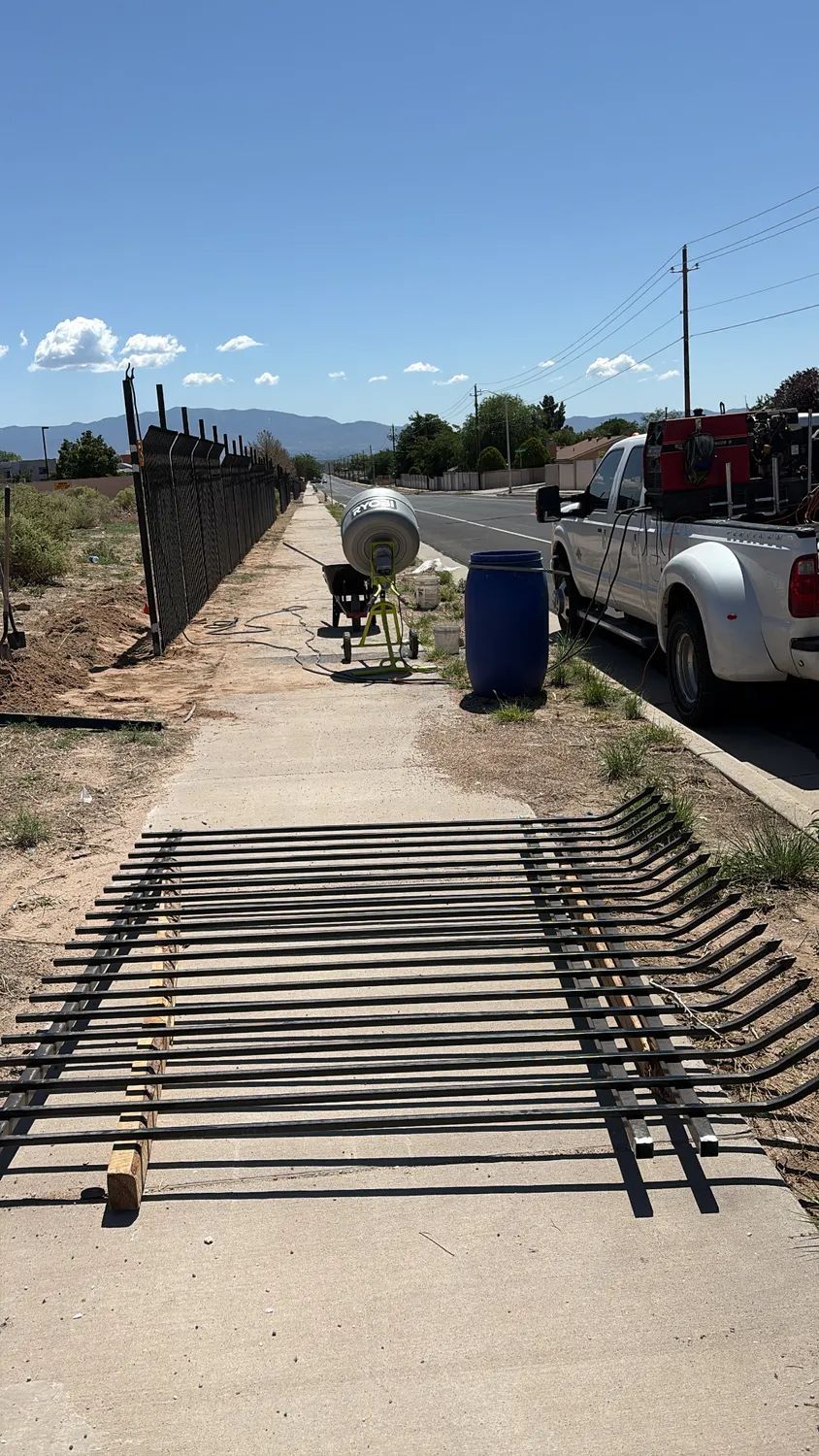 Construction walkway with a wheelchair ramp crossing over a sidewalk trench, beside parked trucks and a work cart.