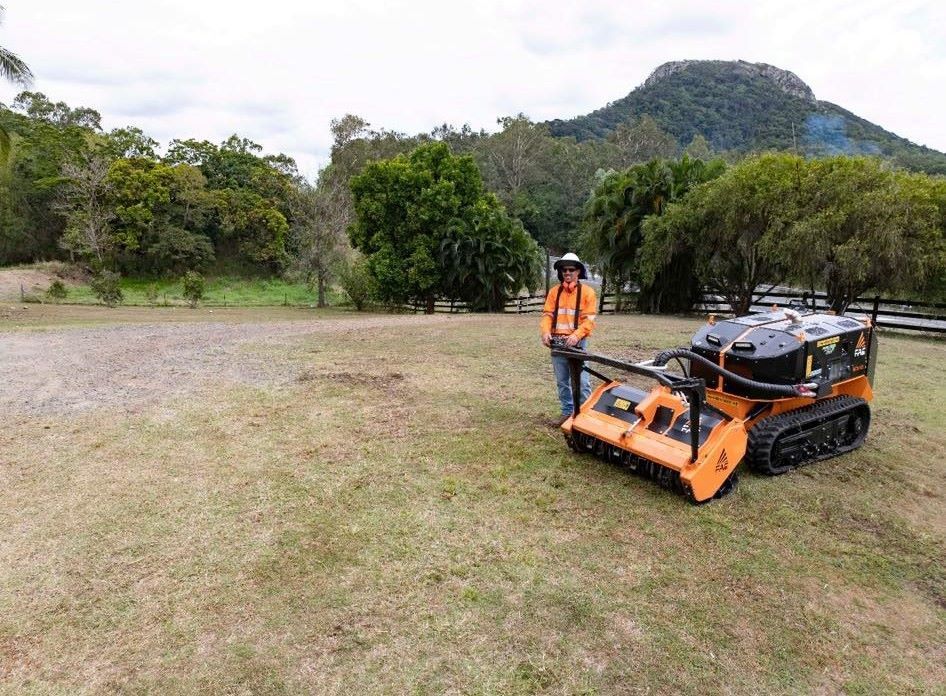 A Man is Standing Next to a Lawn Mower in a Field — NQ Steep Terrain Mulching and Clearing in The Leap, QLD