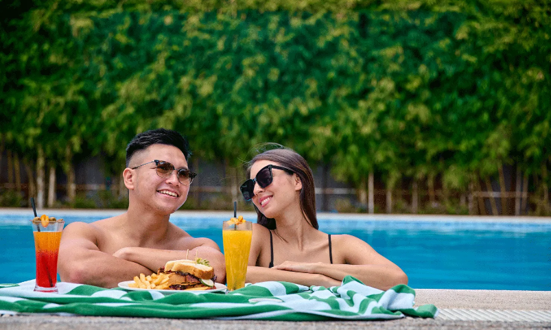 A man and a woman are sitting in a swimming pool with drinks and food in tagaytay