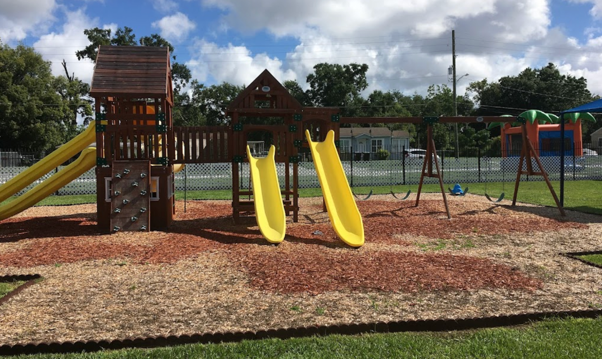 A playground with yellow slides and swings in a park.
