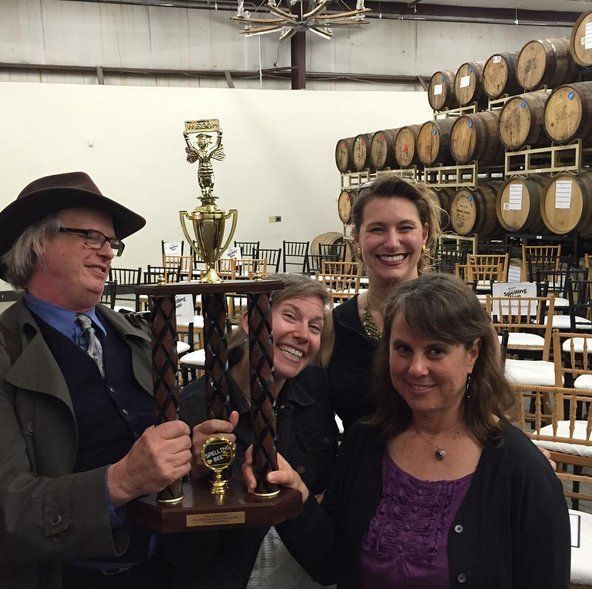 A group of people holding a trophy in front of barrels