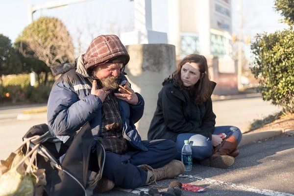 A man and a woman are sitting on the side of the road.