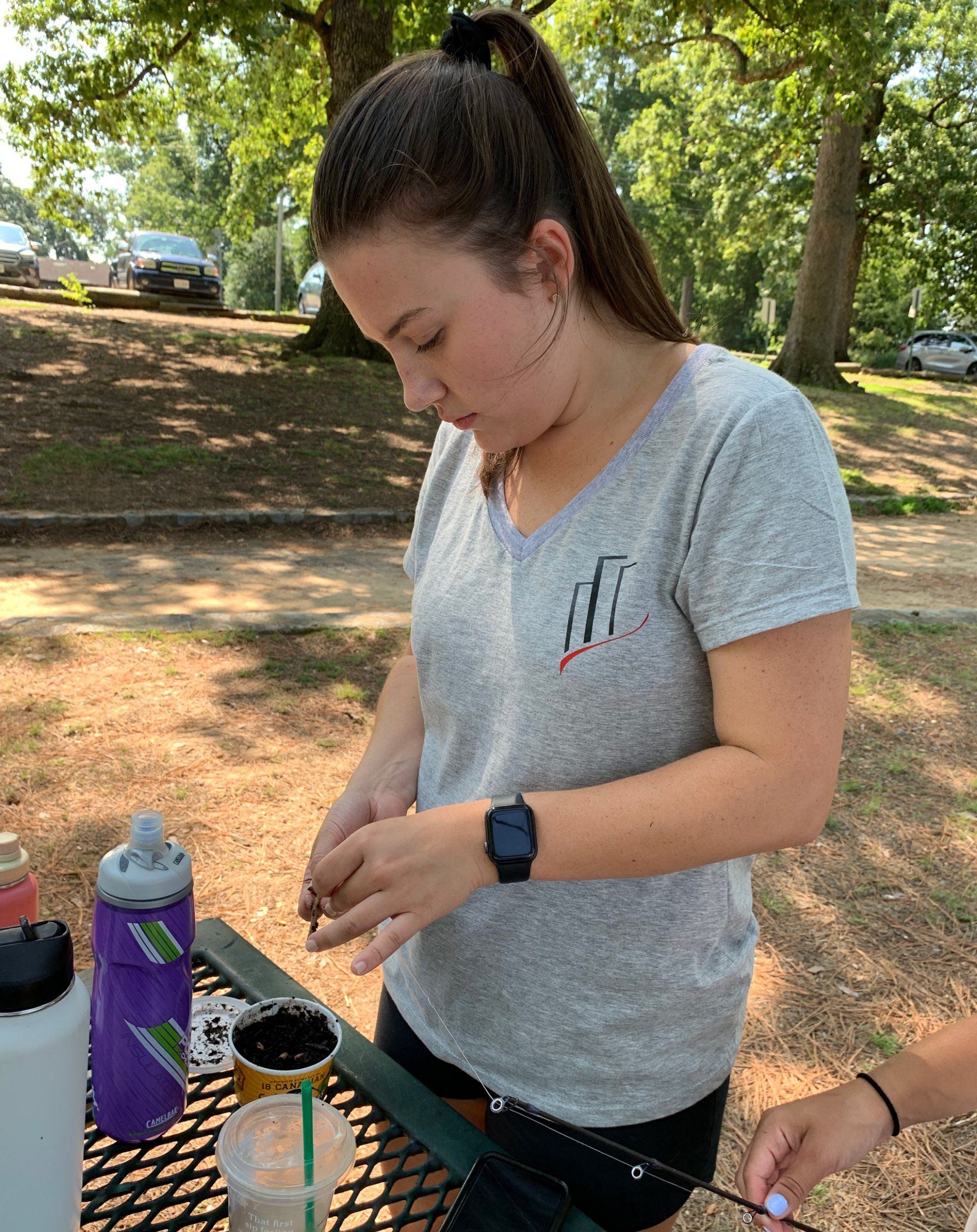 A woman is sitting at a picnic table in a park.