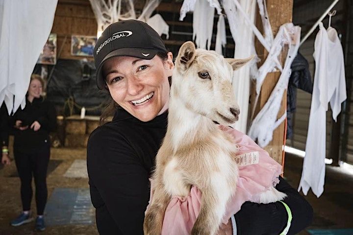 A woman is holding a small goat in her arms.