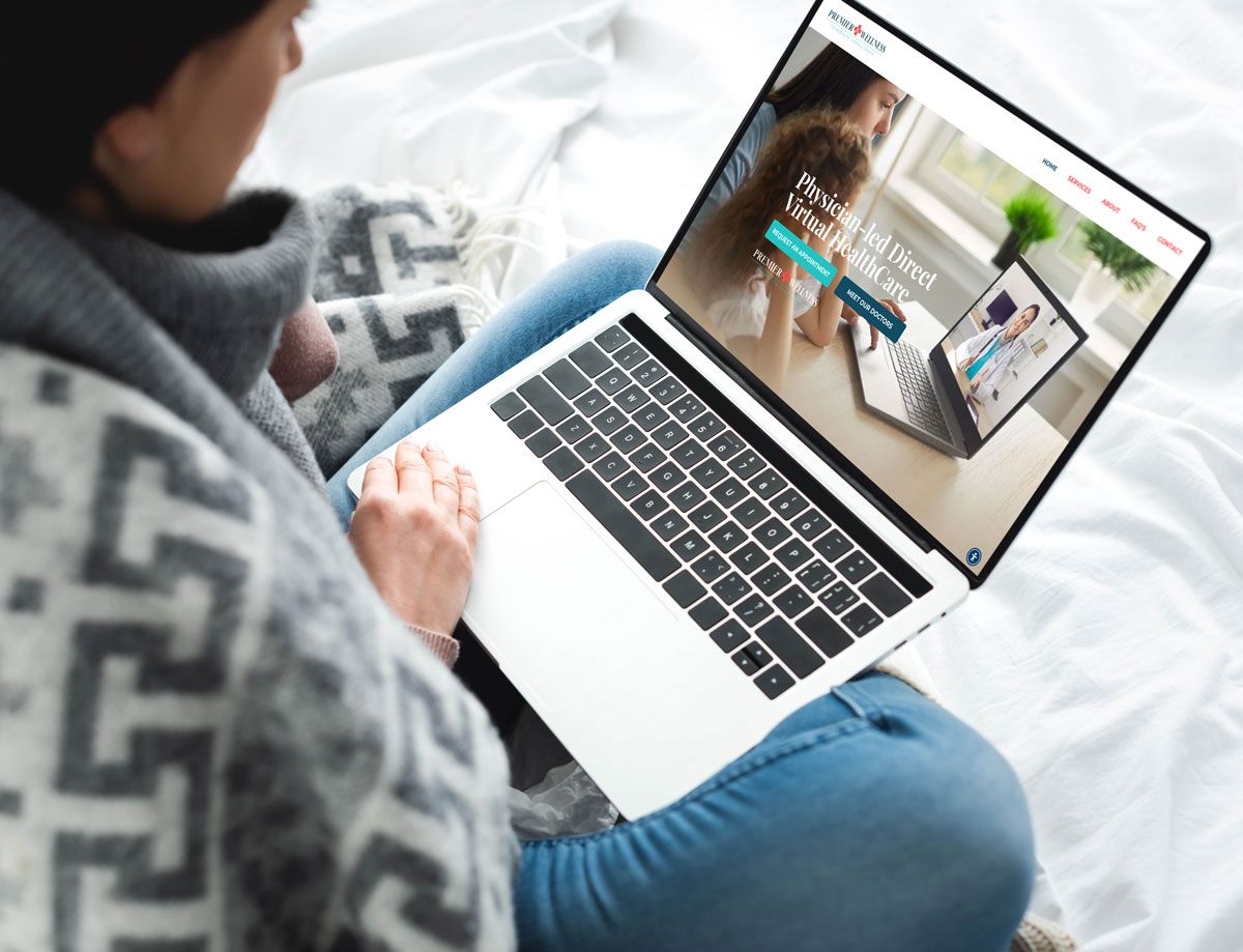 Person sitting on a bed using a laptop; website about pet care displayed on screen.
