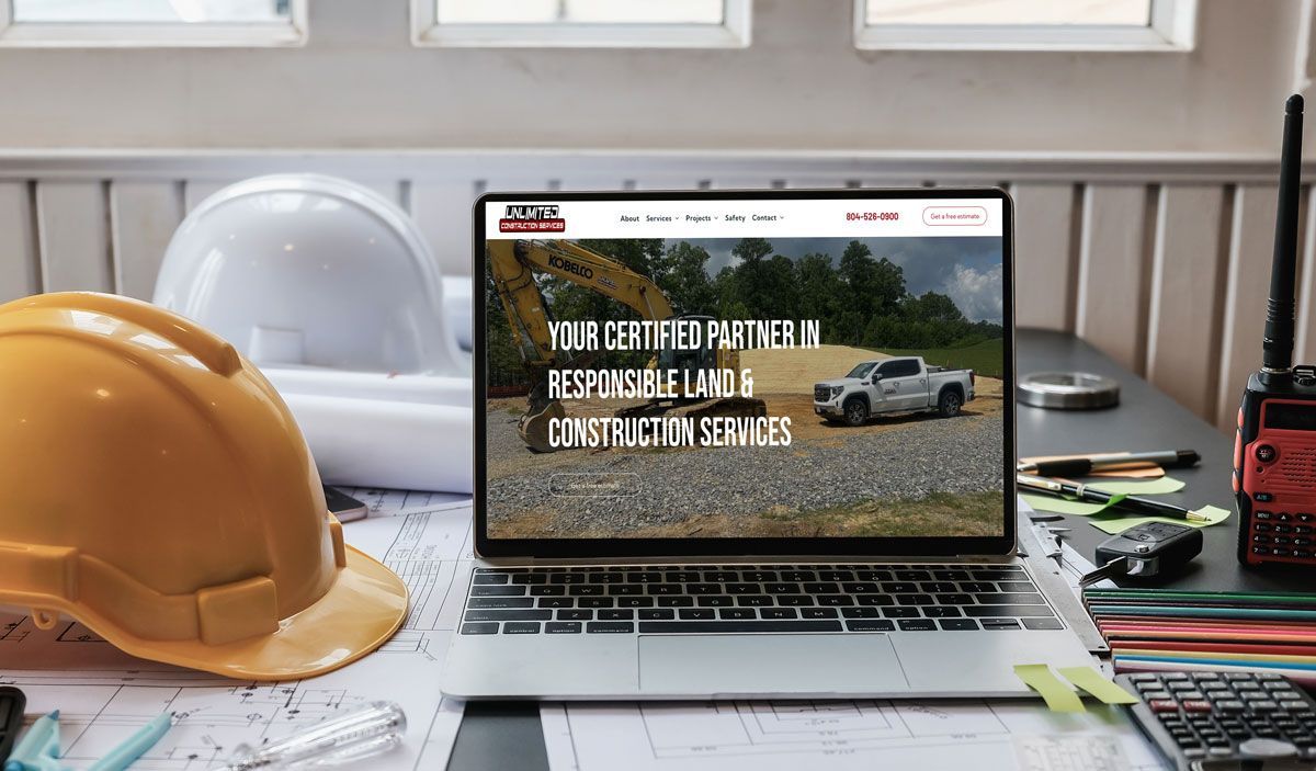 Laptop on a desk with construction tools; website reads