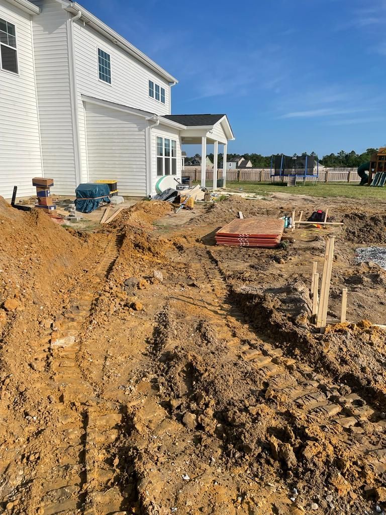 A large pile of dirt is in front of a house under construction.