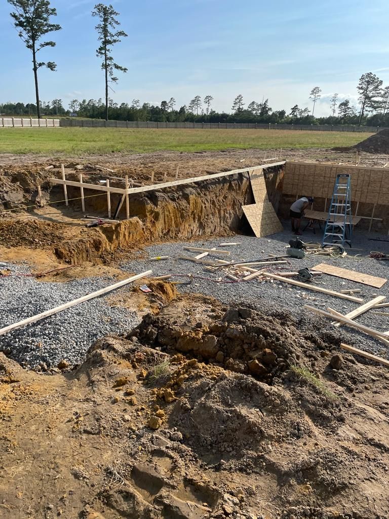 A construction site with a lot of dirt and trees in the background.
