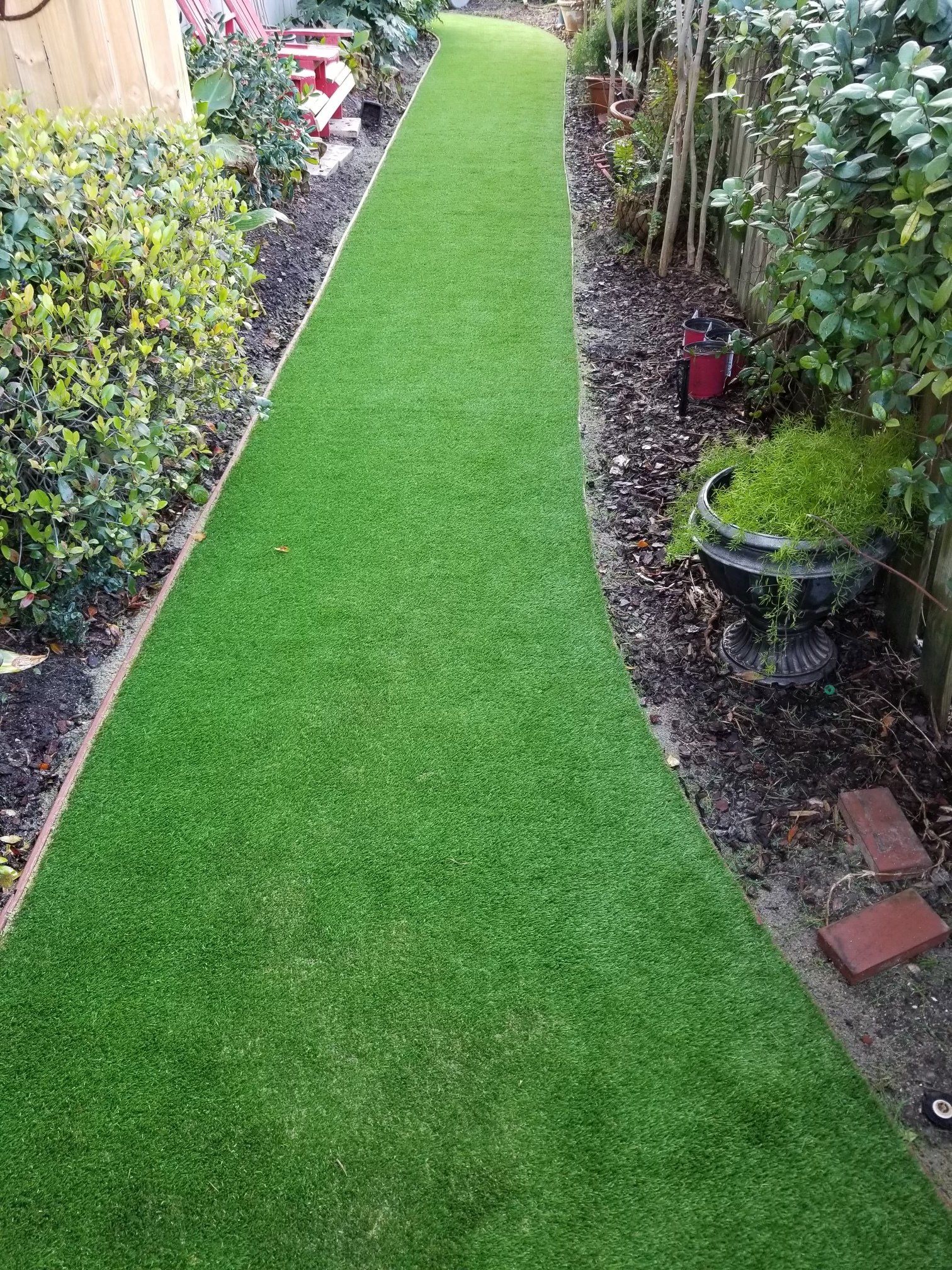 A long grassy path leading to a fence in a garden.