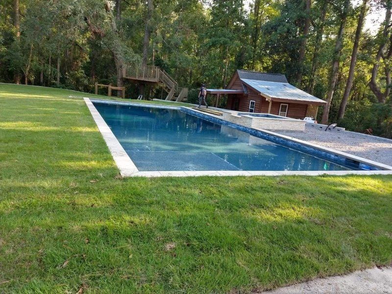 A large swimming pool is in the middle of a lush green field.