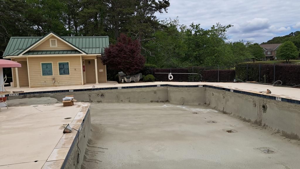 An empty swimming pool with a small house in the background.
