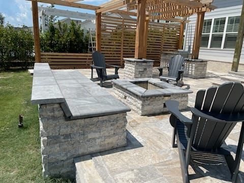 A patio with a fire pit , chairs and a pergola.