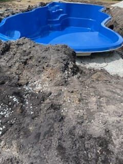 A blue swimming pool is sitting on top of a pile of dirt.