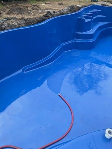 A blue swimming pool with a hose attached to it.