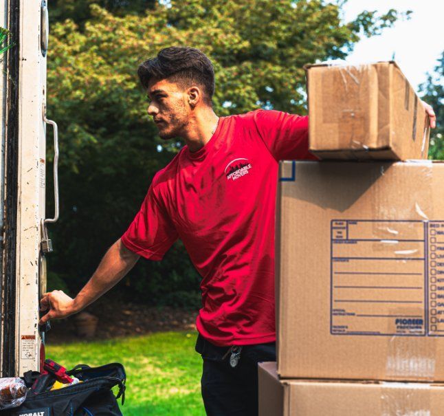 Man in red shirt loads boxes into a truck outdoors.