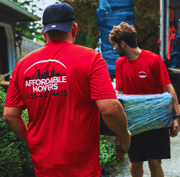 Affordable Movers' team in red uniforms carrying blanket-wrapped furniture in Everett, WA.