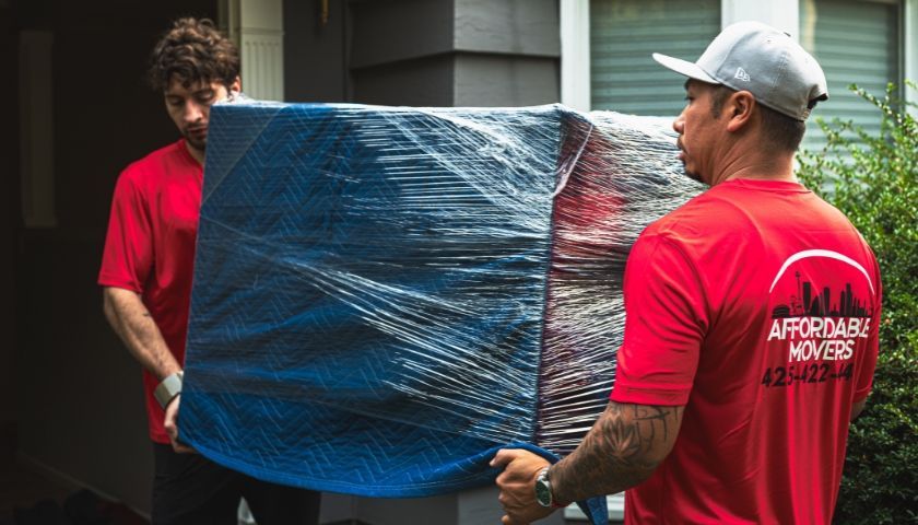 Two Affordable Movers' members carrying wrapped furniture for a residential move in Everett, WA