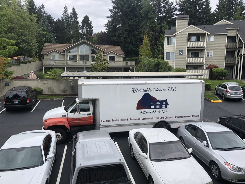Truck with moving company logo parked in front of apartments.