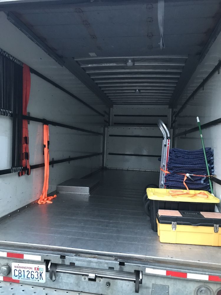 Interior of a truck cargo space; empty except for equipment, straps, and tools.