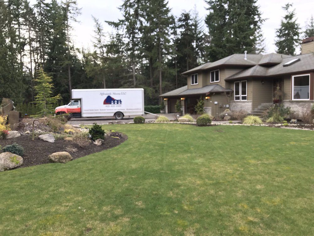 Moving truck in front of a house; green lawn and landscaping.