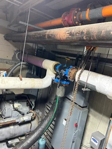 Pipes and machinery in an industrial setting. Several pipes of varying sizes and colors are visible.
