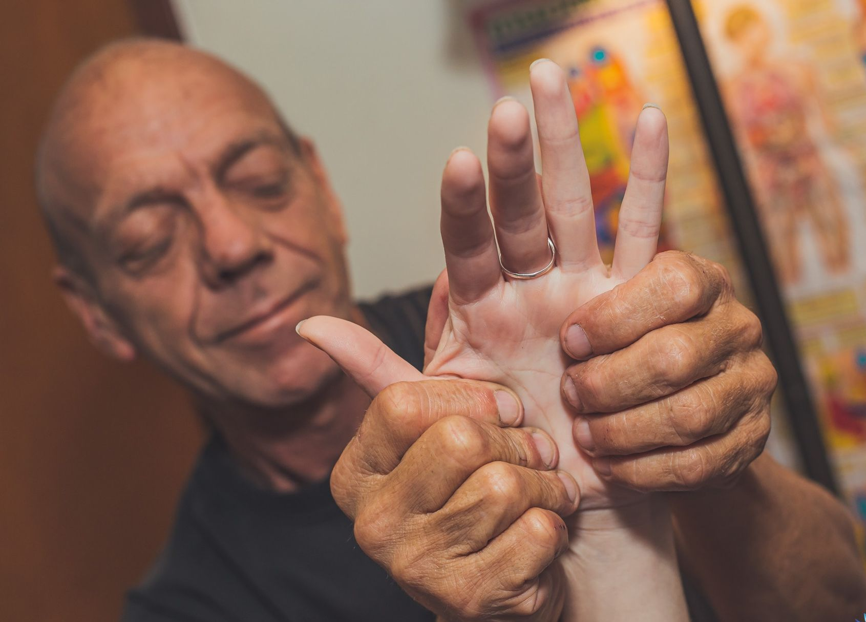 Man applying colorful paint to a raised hand in a warm indoor setting