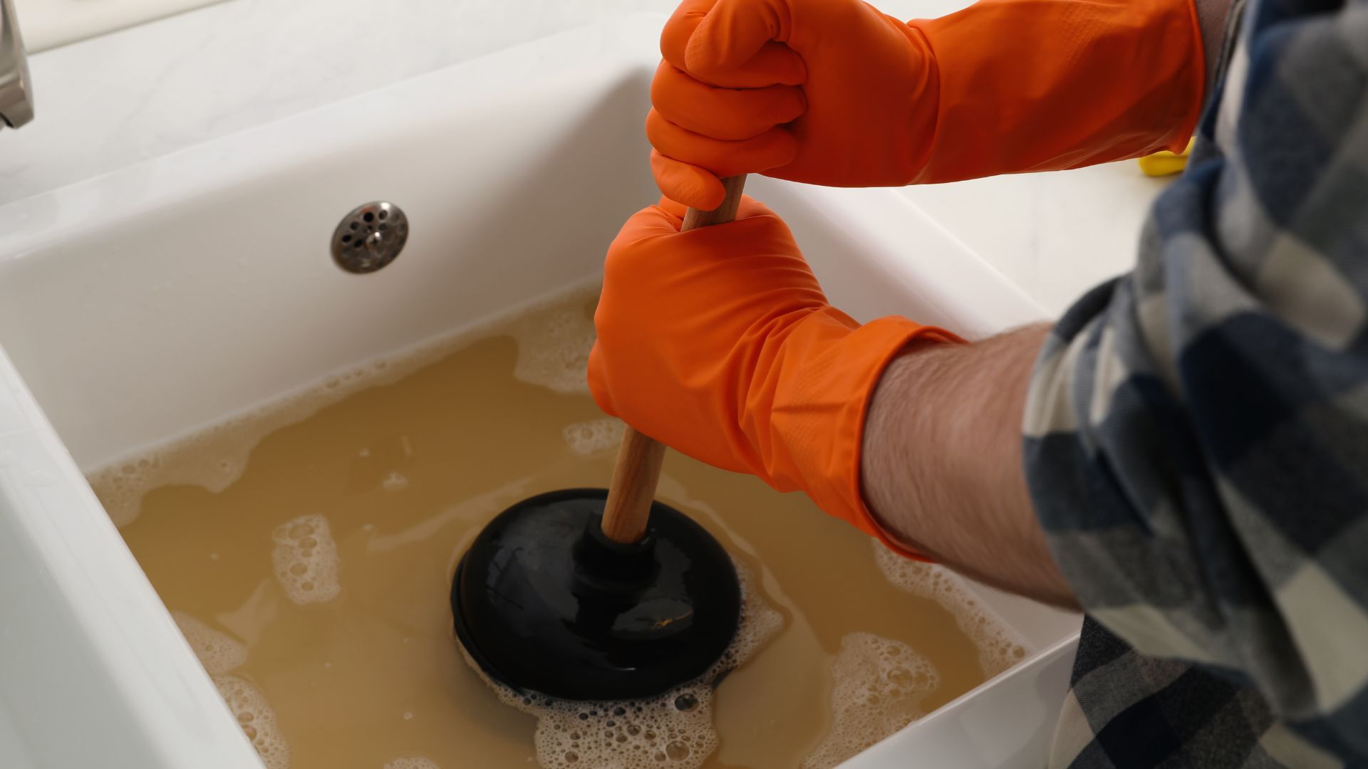 A person is using a plunger to unblock a sink.