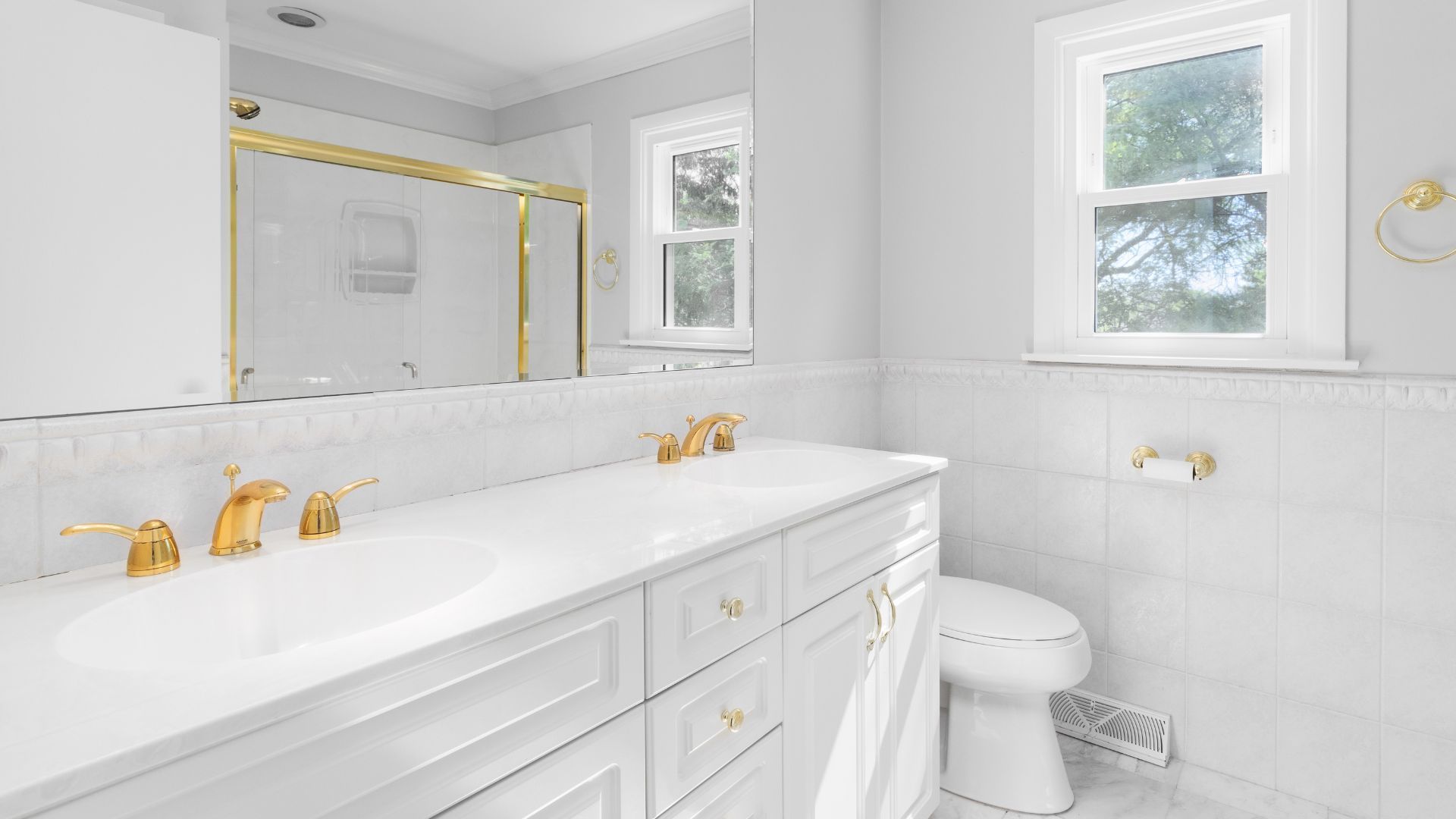A bathroom with a sink , toilet , mirror and window.