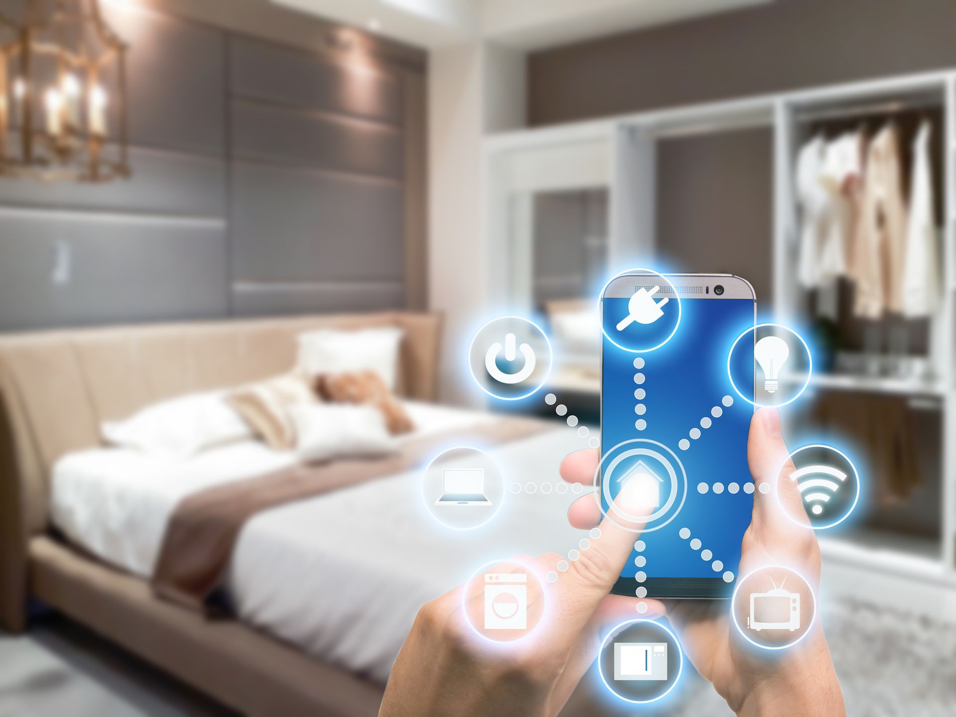 Hand holding phone controlling smart home devices in a bedroom, glowing icons.
