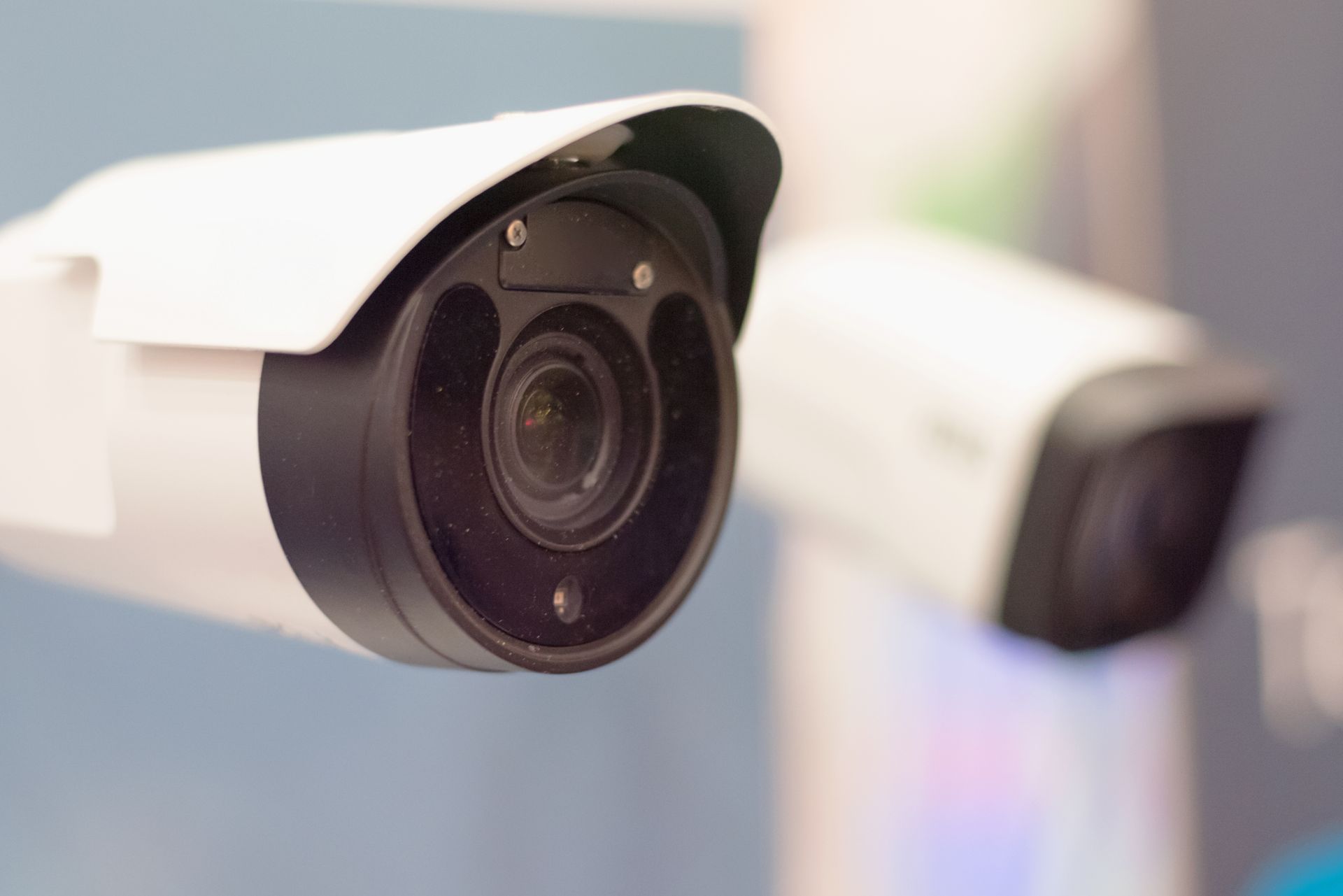 Two white security cameras with black lenses, mounted on a wall.