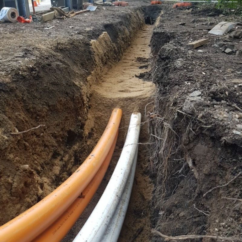 A bunch of pipes are laying in the dirt