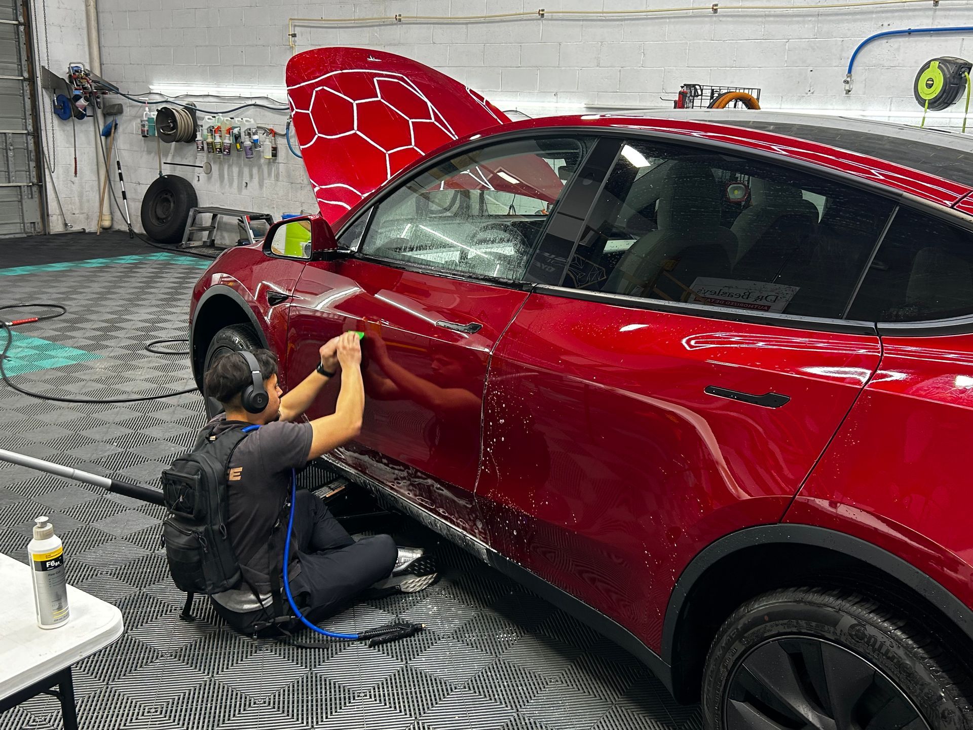 A man is working on a red car in a garage.