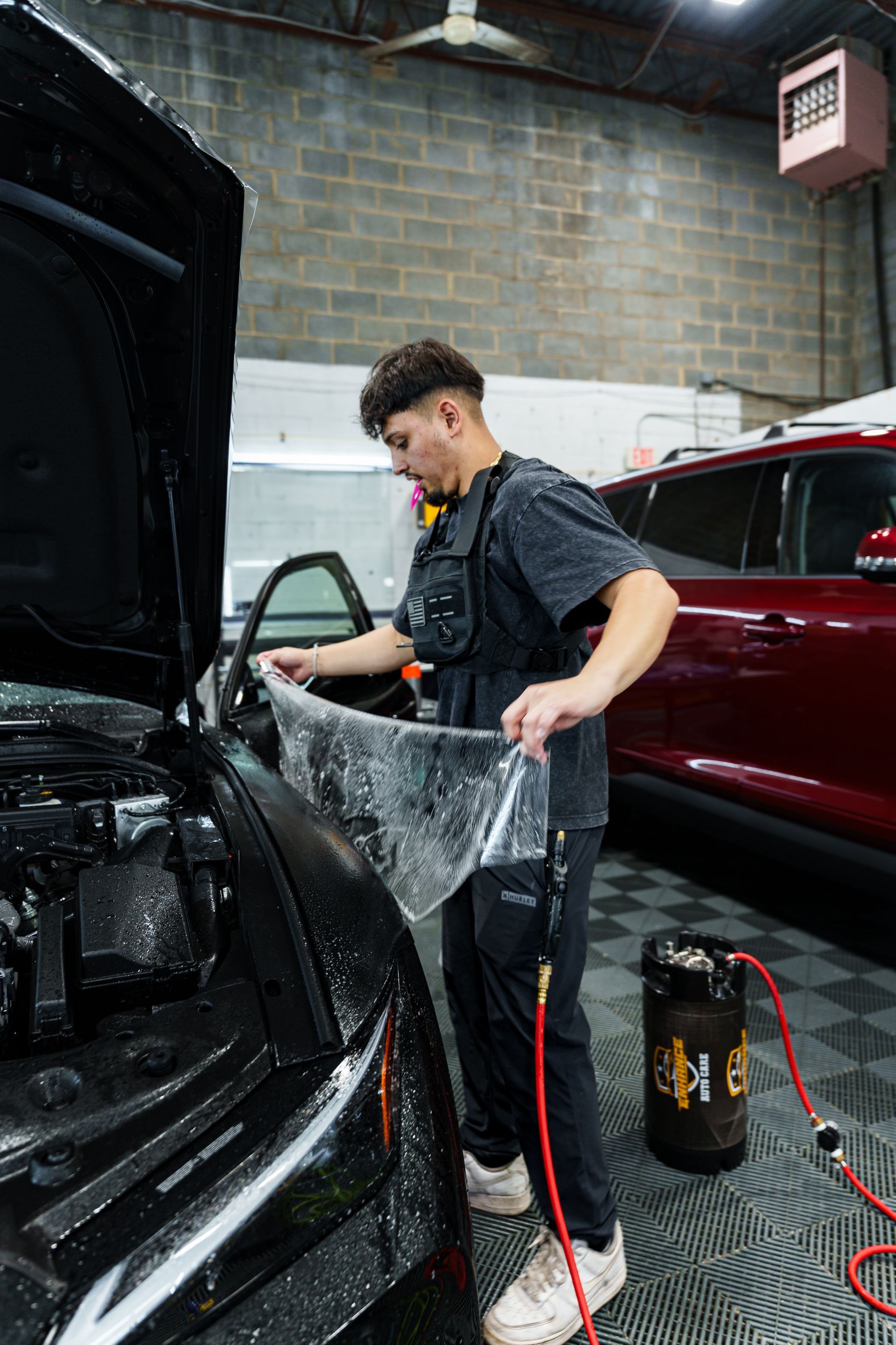 A man is cleaning a white maserati car in a garage.