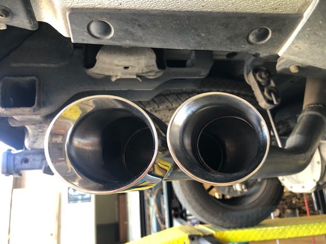 Dual chrome exhaust pipes under a vehicle, viewed from below.