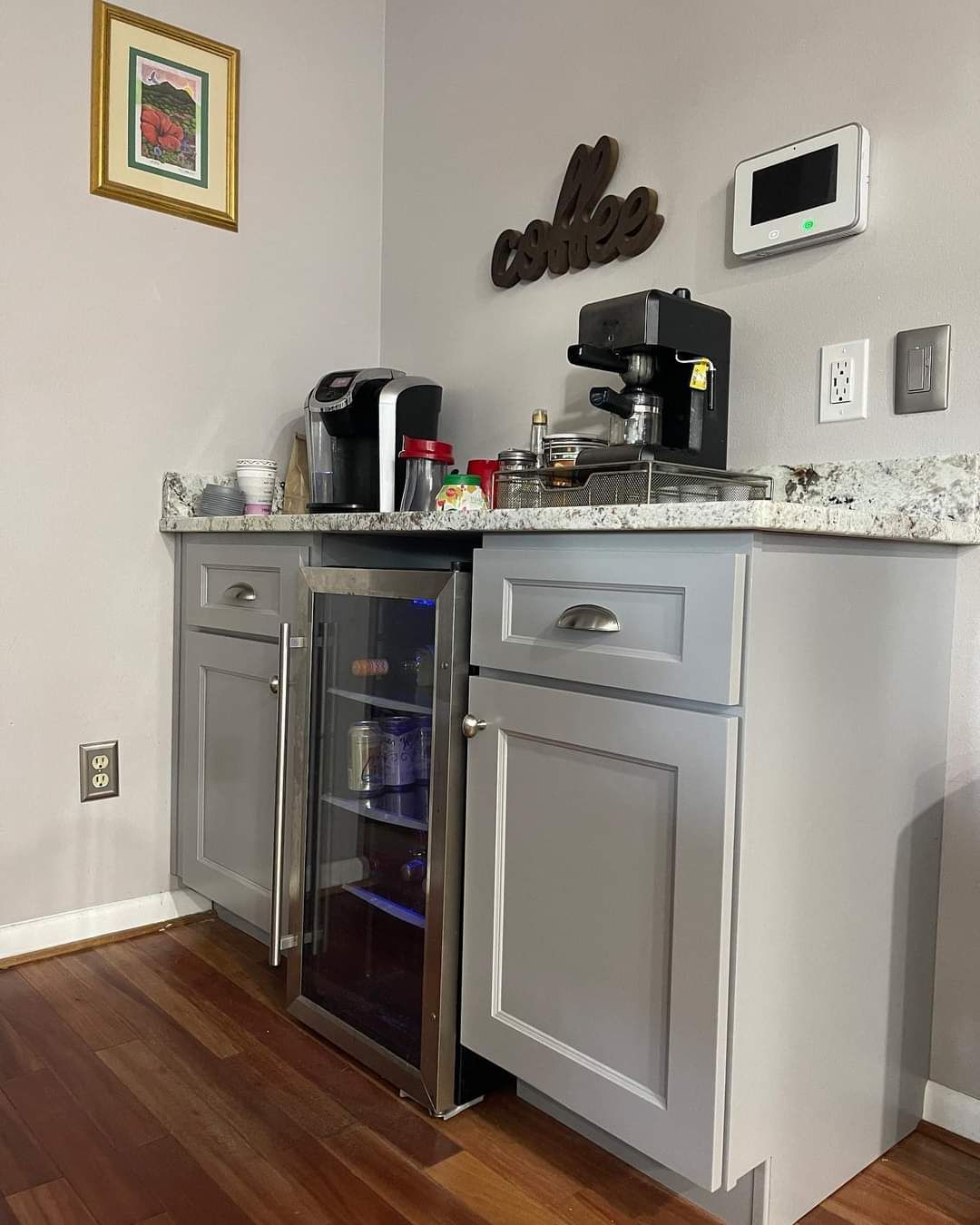 A grey coffee station with two appliances, a small wine cooler, and a